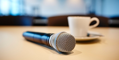 Atmosfera da conferenza stampa: microfono e tazza di caffè su un tavolo.